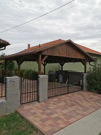 Fa autóbeálló kerítéssel és kapuval, az utca felől